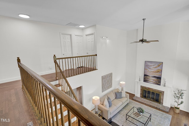 living room featuring a brick fireplace, ceiling fan, and dark hardwood / wood-style floors