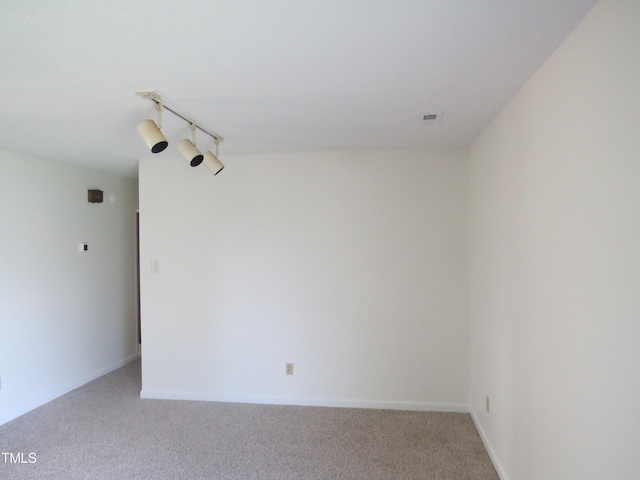 carpeted spare room featuring rail lighting