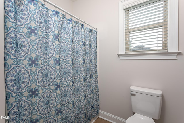 full bath with curtained shower, toilet, and baseboards