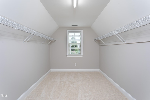 spacious closet with light colored carpet and lofted ceiling