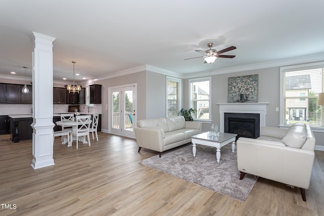 living room with ceiling fan with notable chandelier, light wood-type flooring, and crown molding