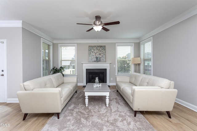 living room featuring light wood finished floors, ornamental molding, and a healthy amount of sunlight