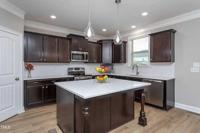 kitchen featuring appliances with stainless steel finishes, a center island, light hardwood / wood-style floors, and decorative light fixtures