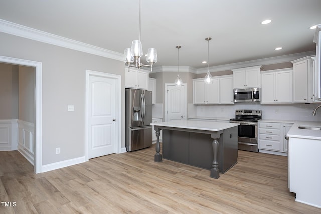 kitchen with a breakfast bar area, a kitchen island, a sink, appliances with stainless steel finishes, and crown molding