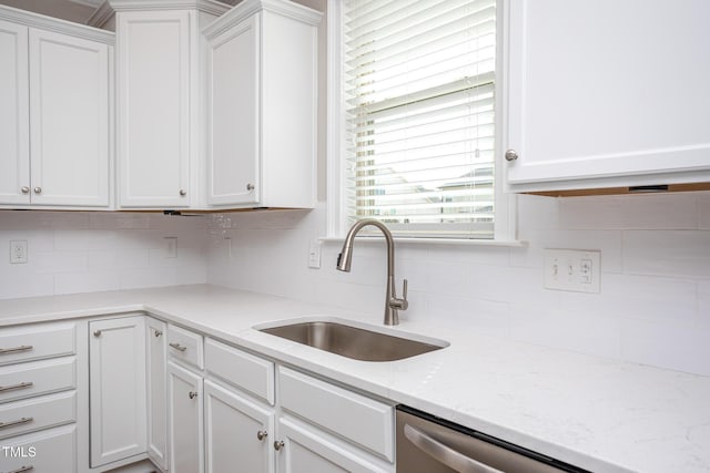 kitchen featuring decorative backsplash, white cabinets, dishwasher, light stone countertops, and a sink