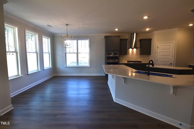 kitchen featuring plenty of natural light, dark wood-type flooring, wall chimney range hood, and a kitchen bar