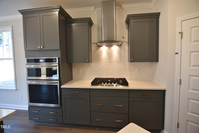 kitchen with wall chimney exhaust hood, stainless steel appliances, tasteful backsplash, gray cabinetry, and ornamental molding