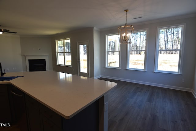 kitchen with hanging light fixtures, dark hardwood / wood-style floors, crown molding, and ceiling fan with notable chandelier