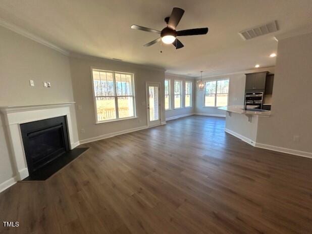 unfurnished living room featuring ceiling fan, crown molding, and dark wood-type flooring