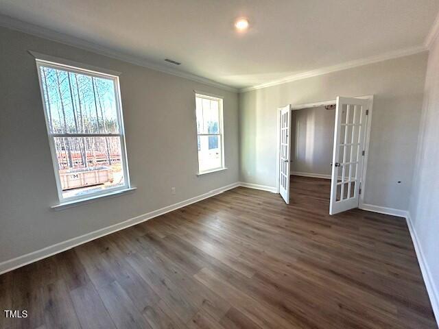 empty room featuring dark wood-type flooring, french doors, and crown molding