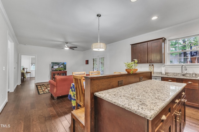 kitchen featuring pendant lighting, ornamental molding, sink, dark wood-type flooring, and a center island