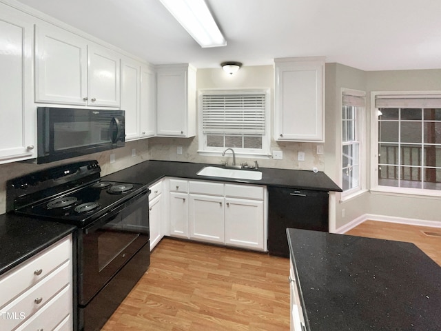 kitchen featuring sink, backsplash, white cabinetry, black appliances, and light hardwood / wood-style floors