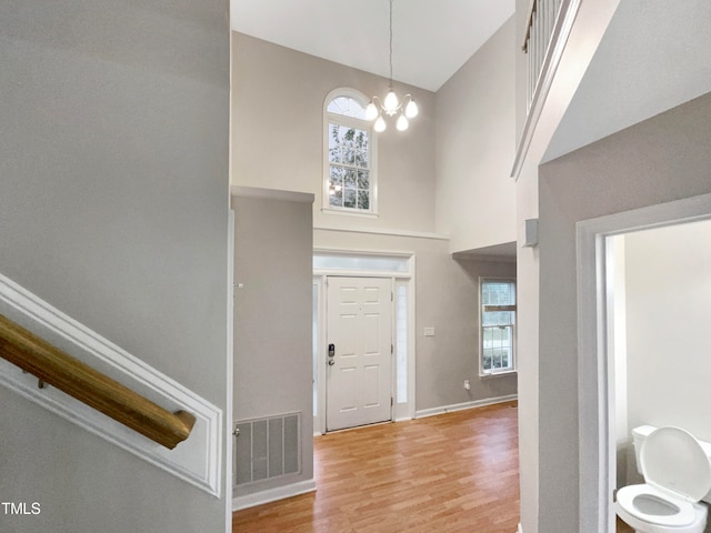 entrance foyer featuring an inviting chandelier, light hardwood / wood-style flooring, and a high ceiling