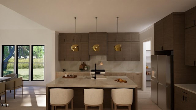 kitchen with sink, a kitchen breakfast bar, white fridge with ice dispenser, and a center island with sink