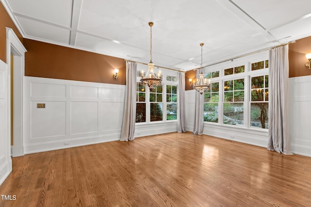 unfurnished dining area featuring hardwood / wood-style floors, an inviting chandelier, coffered ceiling, and crown molding