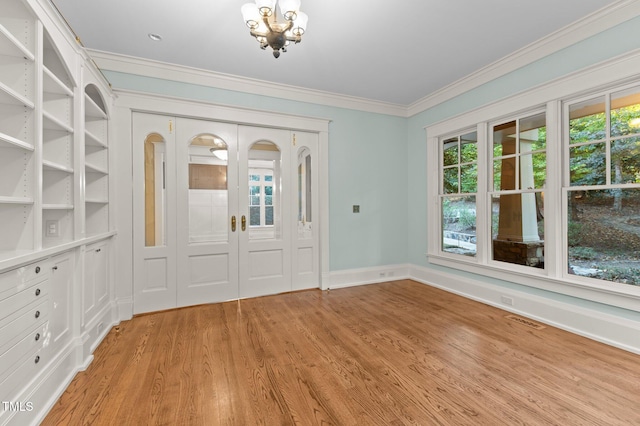 foyer with light hardwood / wood-style flooring, crown molding, and a notable chandelier