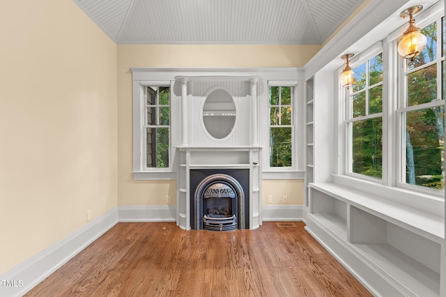 unfurnished living room featuring plenty of natural light, wood-type flooring, and vaulted ceiling