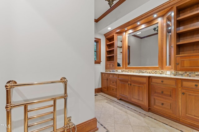 bathroom with tile patterned flooring, vanity, crown molding, and tasteful backsplash