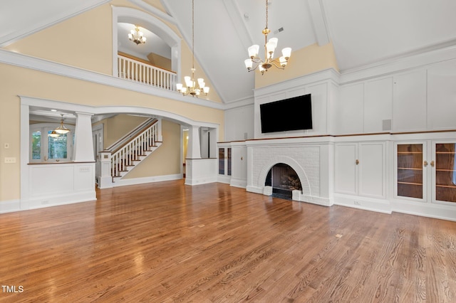 3105 Cone Manor Ln, Raleigh, NC 27613 - unfurnished living room featuring high vaulted ceiling, a chandelier, stairway, wood finished floors, and a brick fireplace