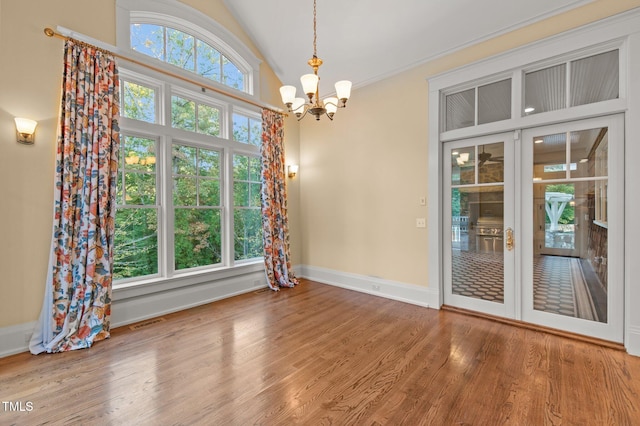 interior space with hardwood / wood-style floors, vaulted ceiling, french doors, and a notable chandelier