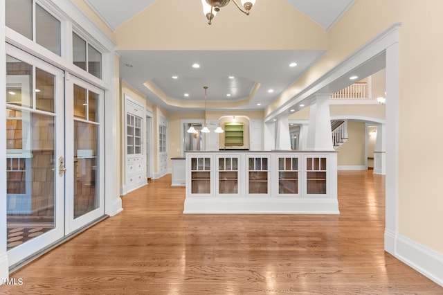 interior space featuring a tray ceiling, pendant lighting, light hardwood / wood-style floors, and french doors