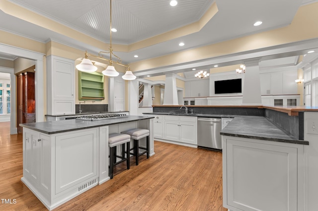 kitchen featuring dishwasher, pendant lighting, a tray ceiling, white cabinets, and light wood-type flooring