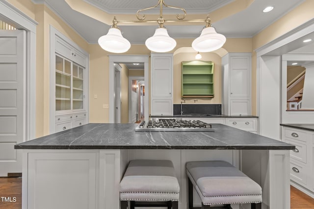 3105 Cone Manor Ln, Raleigh, NC 27613 - kitchen featuring stainless steel gas stovetop, white cabinets, crown molding, a breakfast bar area, and a raised ceiling