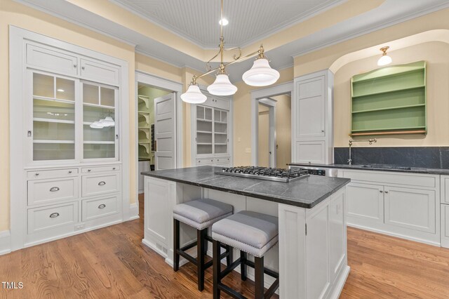 3105 Cone Manor Ln, Raleigh, NC 27613 - kitchen with stainless steel gas cooktop, a kitchen bar, light wood-type flooring, ornamental molding, and a center island