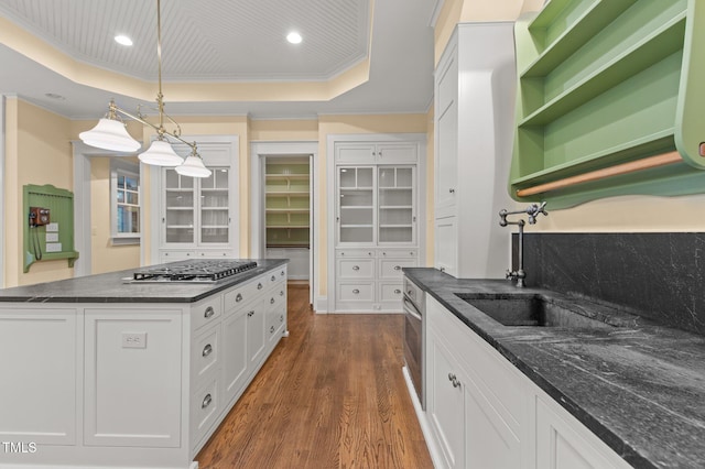 kitchen with dark hardwood / wood-style flooring, pendant lighting, a tray ceiling, white cabinets, and ornamental molding