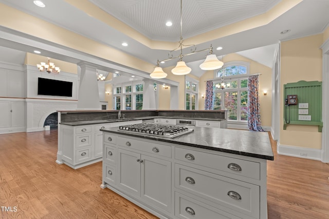 kitchen with a tray ceiling, crown molding, a center island, and light wood-type flooring