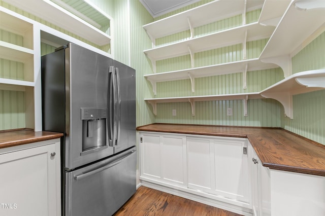 kitchen with white cabinets, dark hardwood / wood-style floors, stainless steel fridge with ice dispenser, and wooden counters