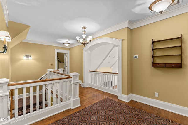 hallway with a chandelier, wood-type flooring, and crown molding