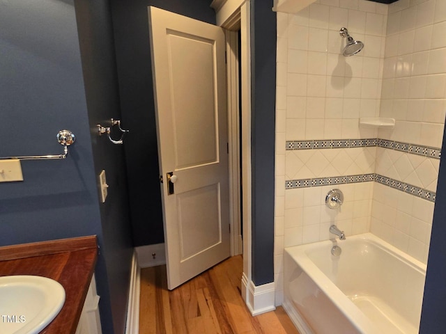 bathroom with hardwood / wood-style flooring, vanity, and tiled shower / bath