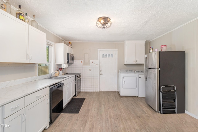 kitchen with white cabinets, washer and clothes dryer, appliances with stainless steel finishes, tile walls, and light hardwood / wood-style floors