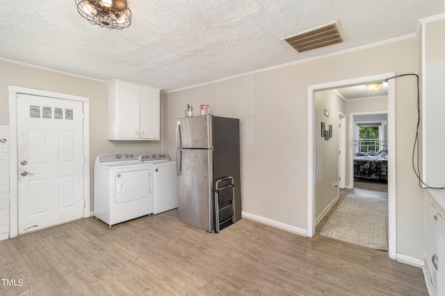 laundry area featuring ornamental molding, light hardwood / wood-style floors, independent washer and dryer, and cabinets