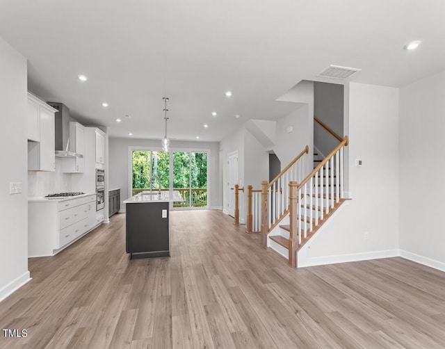 4505 Mint Leaf Ln, Raleigh, NC 27612 - kitchen featuring wall chimney exhaust hood, light countertops, white cabinets, light wood-style flooring, and recessed lighting
