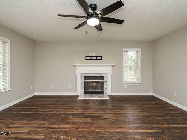 unfurnished living room with a textured ceiling, plenty of natural light, ceiling fan, and dark hardwood / wood-style flooring