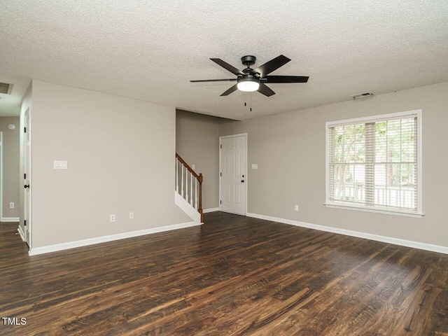 empty room with a textured ceiling, ceiling fan, and dark hardwood / wood-style flooring