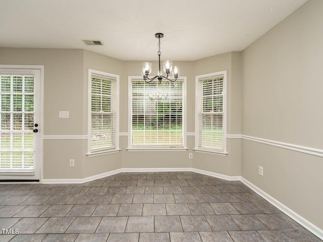 unfurnished dining area with a notable chandelier, tile patterned flooring, and plenty of natural light