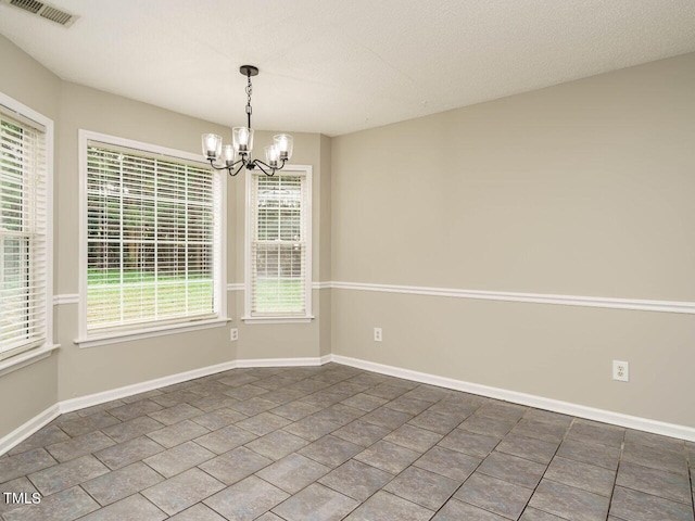 tiled spare room with a notable chandelier and a textured ceiling