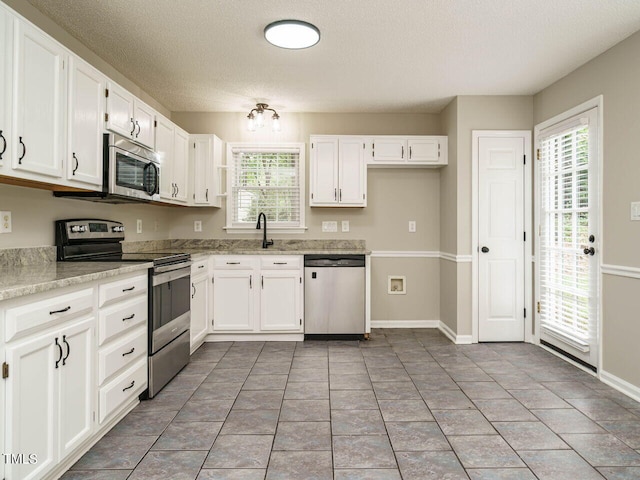 kitchen featuring white cabinets, a textured ceiling, appliances with stainless steel finishes, and sink