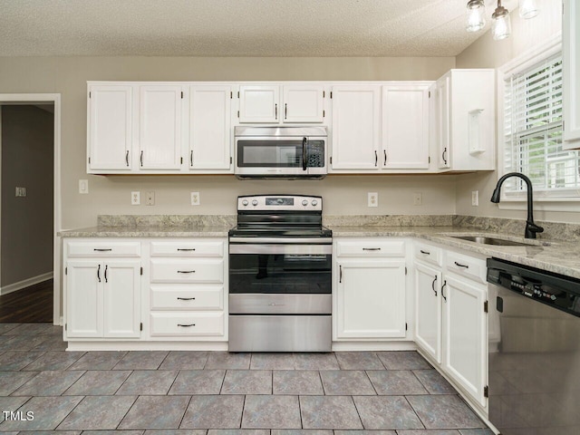 kitchen featuring light stone countertops, stainless steel appliances, white cabinetry, and sink