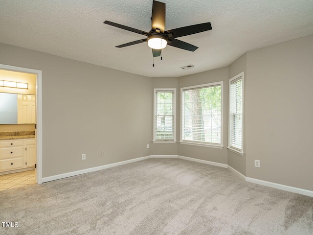 carpeted empty room featuring ceiling fan and a textured ceiling