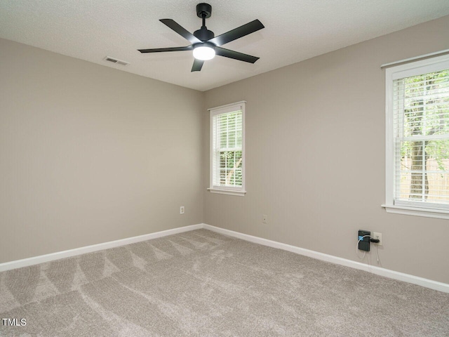 carpeted spare room with ceiling fan, a textured ceiling, and plenty of natural light