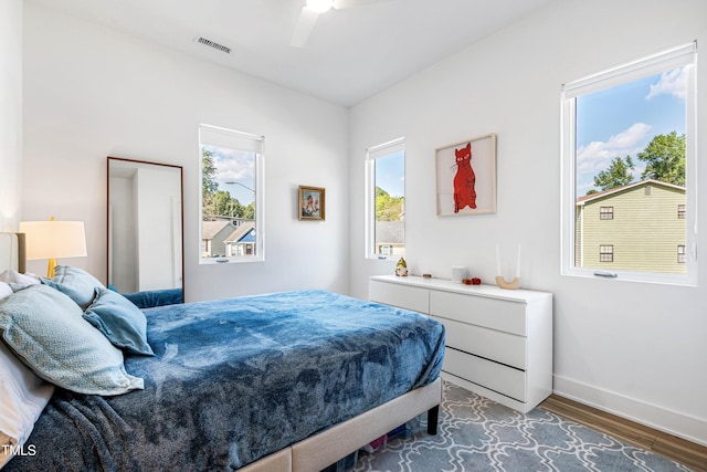 bedroom with baseboards, visible vents, a ceiling fan, and wood finished floors