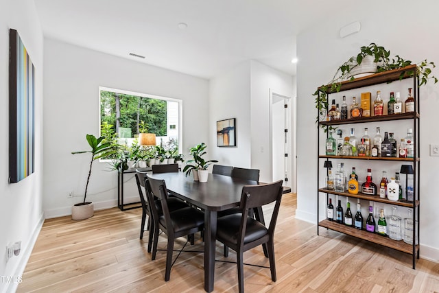 dining area featuring baseboards, light wood-type flooring, and visible vents