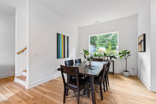 dining space featuring baseboards, stairway, light wood-style flooring, and visible vents