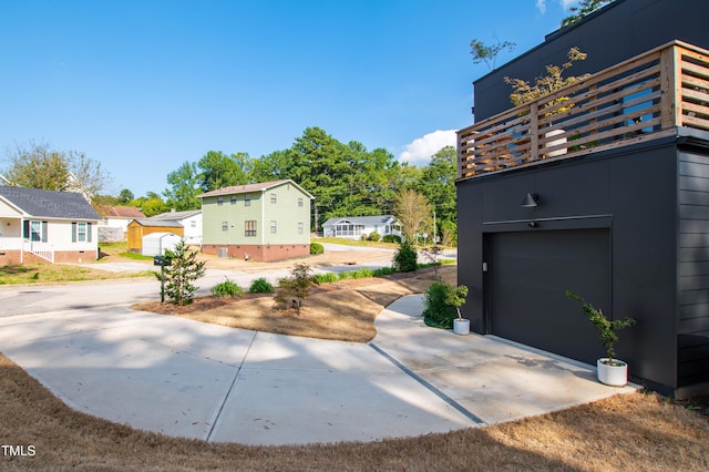 view of property exterior with a balcony, an attached garage, and driveway