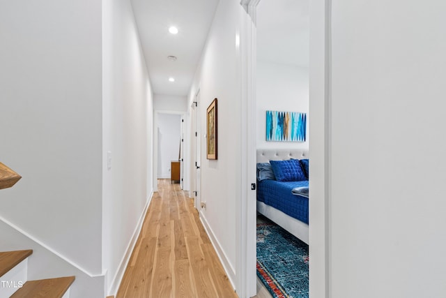 hall with baseboards, light wood finished floors, and recessed lighting