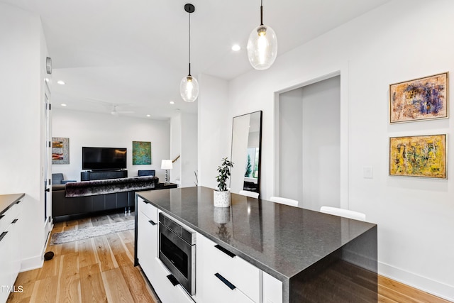 kitchen featuring hanging light fixtures, light wood-style flooring, white cabinetry, stainless steel microwave, and recessed lighting